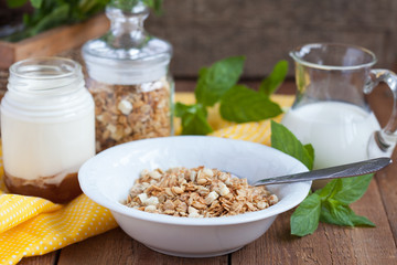Breakfast: homemade granola in a white plate, yogurt with jam 