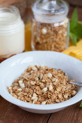 Breakfast: homemade granola in a white plate and yogurt with jam