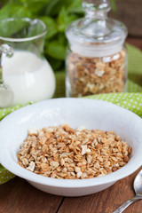 Breakfast: homemade granola in a white plate and yogurt with jam
