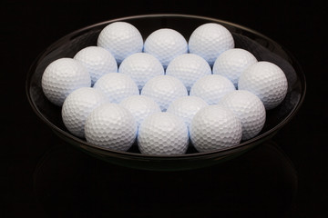 Black ceramic bowl full of golf balls