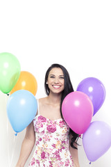 Fototapeta na wymiar Smiling Young Pretty Brunette Woman holding Colorful Balloons