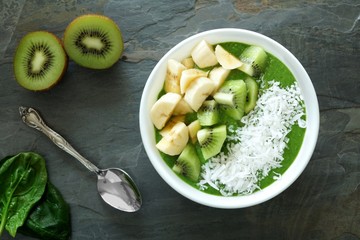 Green smoothie bowl with spinach, bananas, kiwi and coconut