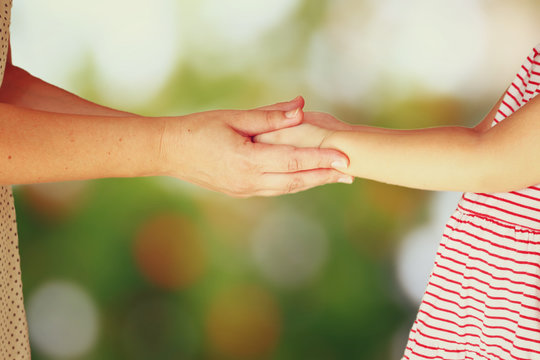 mother and child holding hands over blurred background
