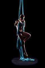 Obraz na płótnie Canvas Young woman gymnast with blue gymnastic aerial silks