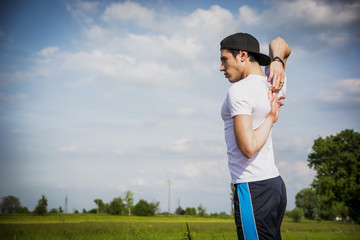 Athletic, fit young man outdoor in country doing stretching
