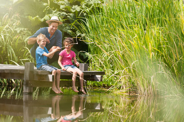 a father with his son and daughter engaged in fishing in a river