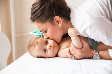 Mother playing with her baby on the bed at home.