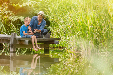 On a wood pontoon, father teaching his young son to respect nature