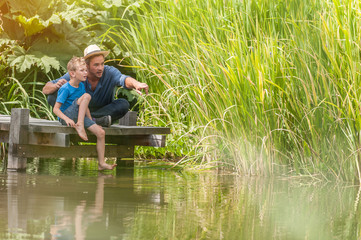 On a wood pontoon, father teaching his young son to respect nature