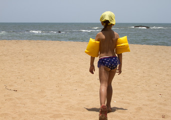 Beautiful little girl standing on the sandy beach. India, Goa
