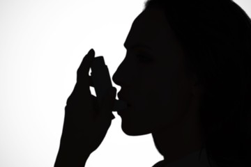 Composite image of asthmatic brunette using her inhaler 