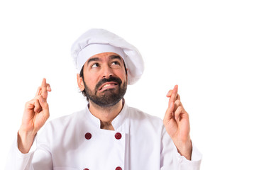 Chef with his fingers crossing over white background