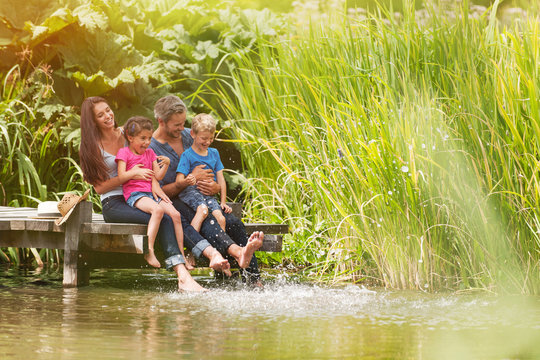 happy family sitting at the edge of a pontoon, feet in the river