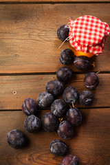 Sweet plums and honey jar on old wooden kitchen table