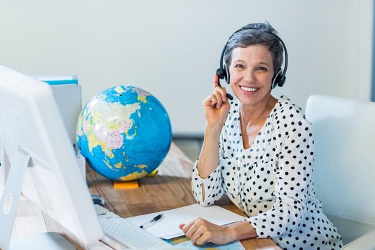 Smiling travel agent sitting at her desk