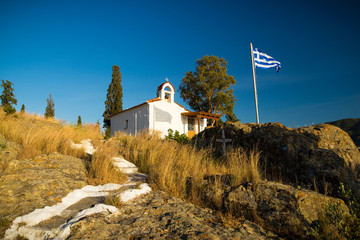 kleine Kirche mit griechischer Fahne auf Poros - obrazy, fototapety, plakaty
