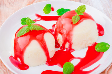 Panna Cotta with raspberry sauce on wooden table