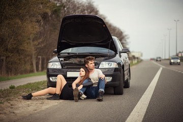 couple near a broken car on the roadside