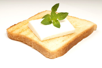 A crusty toasted bread with cheese and a basil leave isolated