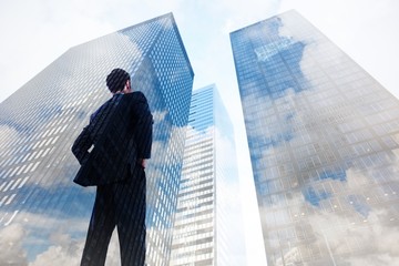 Fototapeta premium Composite image of businessman standing with hands on hips