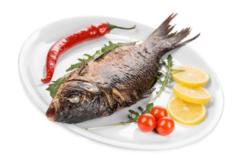 Grilled carp with vegetables on plate.