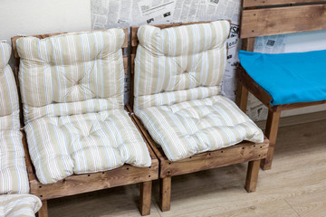 Soft pillows on wooden hand made chairs and bench