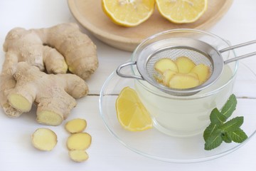 Ingwertee mit Zitrone und Minze in Teetasse, Sieb