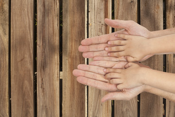 father and son holding hands on wooden background