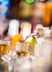 Barman pouring hard spirit into glasses