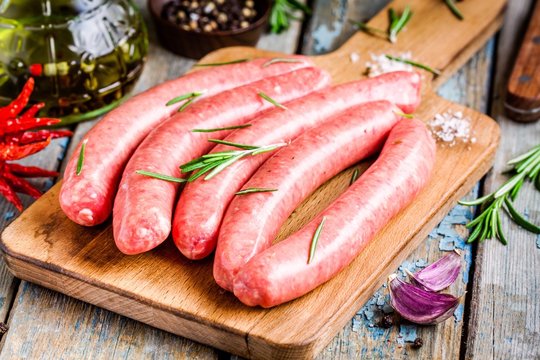 raw homemade sausages on cutting board  with rosemary