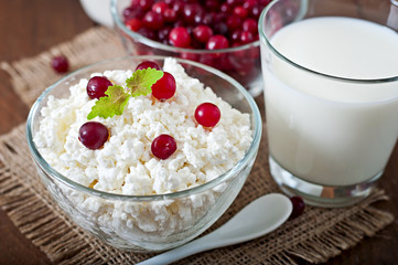 Cheese, milk and cranberries on a wooden table 