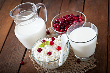 Cheese, milk and cranberries on a wooden table 