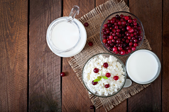 Cheese, milk and cranberries on a wooden table 