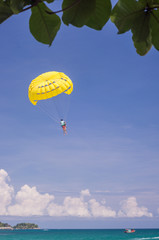 Yellow parachute soaring over the blue waters below
