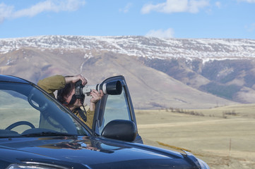 Fototapeta na wymiar Photographer taking pictures of a mountain chain in Altai