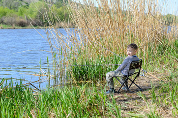 Fototapeta na wymiar Smiling Young Boy Sitting on a Chair While Fishing
