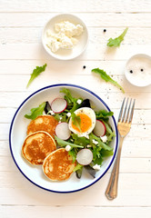 pancakes and egg salad on a light wooden surface