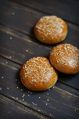 homemade buns for burgers on dark wooden surface