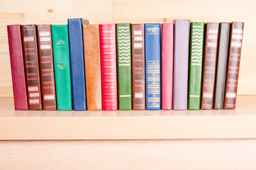 Old colorful books on wooden shelf