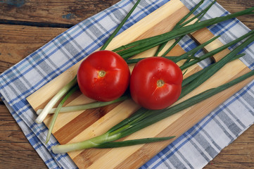 Помидоры и зеленый лук на разделочной доске