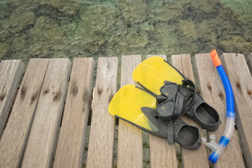 Scuba mask with yellow flippers on wooden pier background