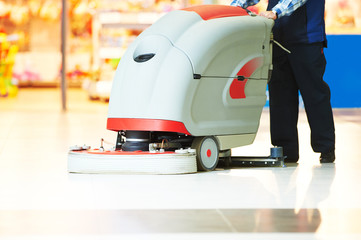 worker cleaning store floor with machine