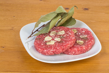 two fresh raw hamburgers seasoned with garlic salt and pepper