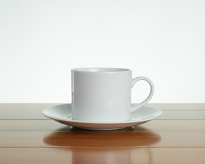 Empty white mug with saucer on wood