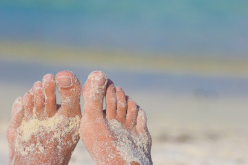 Close up of female feet on white sandy beach