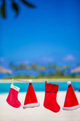 Red Santa hats and Christmas stocking hanging on tropical beach