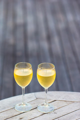 Two glasses of tasty white wine at sunset on wooden table