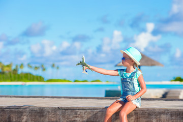 Fototapeta premium Happy little girl with toy airplane in hands on white sandy