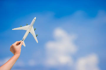 Small white miniature of an airplane on background of blue sky