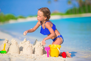 Adorable little girl playing with beach toys during tropical